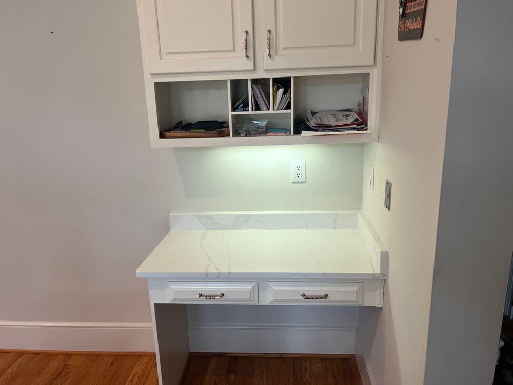 Home office nook with white countertop, cabinetry, and organized storage space. Perfect for productivity.